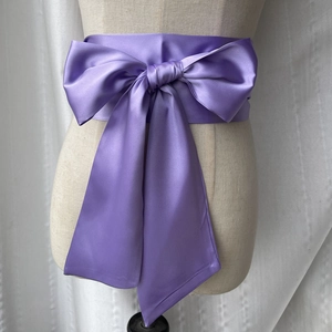 Détail de la ceinture de taille en satin violet avec un nœud soyeux noué sur un mannequin