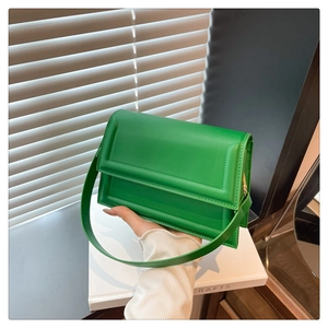 Detail of hand-held green leather square shoulder bag with flap design and metal clasp