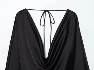 Détail d'une robe en satin noir avec col bénitier drapé et fines bretelles à nouer