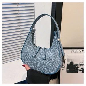 Blue woven crescent underarm bag with silver hardware on minimalist white background