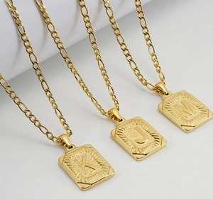 Détail de chaînes Figaro dorées avec pendentifs carrés gravés des lettres K, J et M