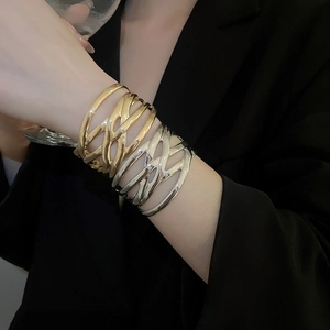 Close-up of irregular wide hollow metal cuff bracelets in gold and silver finish