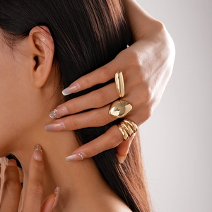 Detail of three gold oval bean rings with polished finish worn by a model