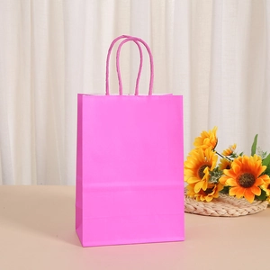 Rose pink kraft paper gift bag with rope handles on a wooden table with sunflower decor