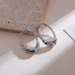 Detailed macro view of silver star stud earrings with a textured hammered finish on stone