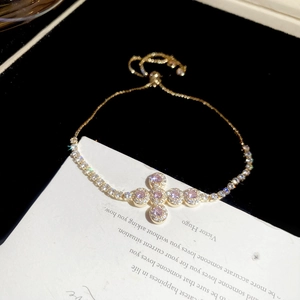 Detail of adjustable gold bracelet with pink crystal cross pendant and micro zircon stones