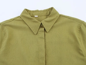 Detailed view of the olive green linen shirt's pointed collar and woven fabric texture