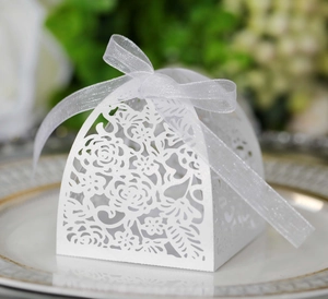 Detail of white laser-cut wedding candy box with elegant floral hollow out and ribbon