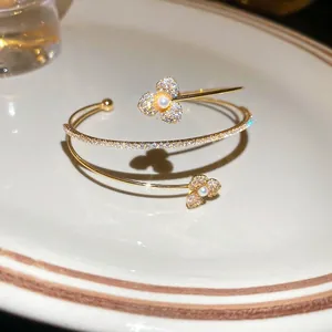 Elegant gold double-layered flower bangle with cubic zirconia and pearls in a warm setting