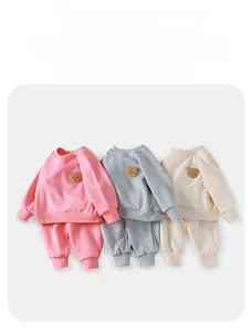Detailed view of kids fleece bear tracksuits in pink, grey, and off-white colors