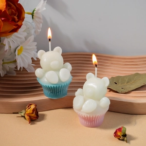 Détail d'une bougie muffin ours en 3D allumée montrant la flamme et la cire de soja