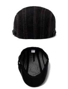 Detail of black denim beret showing orange stitching and 100% cotton inner label