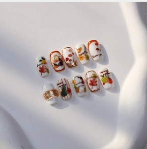 Macro view of 5D autumn themed nail art stickers with hand-painted leaves and fruits