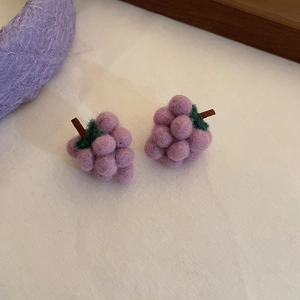 Macro detail of handmade purple grape-shaped wool felt earrings with green leaf accent