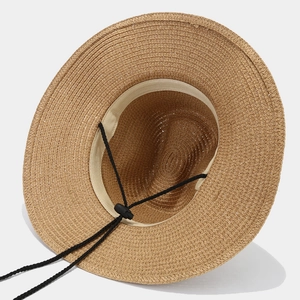 Detail of hand-woven straw hat interior featuring adjustable black lanyard and sweatband