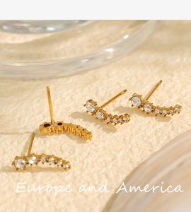 Macro shot of gold crescent stud earrings with inlaid zircons in a curved arrangement