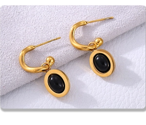 Dettaglio di orecchini a C placcati oro 18K con ciondoli ovali in agata nera su sfondo grigio