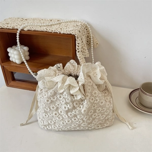 Detailansicht der cremefarbenen Spitzenbeuteltasche mit Blumenstickerei und Perlenkette