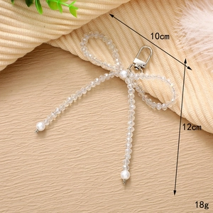 Detailed macro view of handmade pearl bow charm with dimensions 10x12cm and lobster clasp