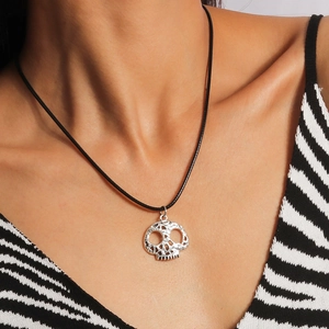 Close-up of a silver skeleton head pendant necklace with a black cord on a model