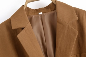 Macro detail of brown blazer notch lapel showing premium fabric texture and neat stitching