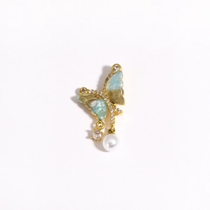 Close-up of asymmetric butterfly earring with blue enamel, zircons and pearl drop