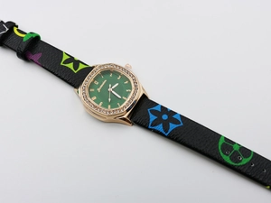 Detail view of square gold watch case with crystal bezel and green sunray dial