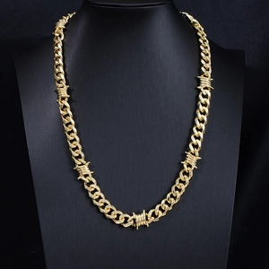 Detail of a gold Cuban link chain with thorn wire accents on a black mannequin