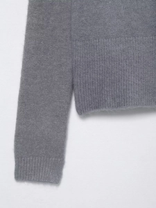 Dettaglio della trama a maglia fine e dei polsini a costine di questo maglione di lana grigio
