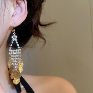 Close-up of elegant gold leaf tassel earrings with sparkling rhinestones on model