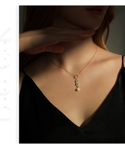 Close-up of elegant gold necklace featuring a pearl pendant on a model's neck