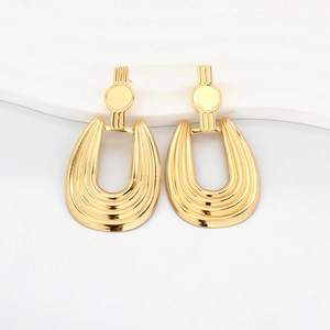 Detailed close-up of golden geometric earrings with textured relief on white display