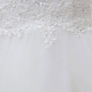 Close-up of white lace embroidery and shimmering sequins on a bridal gown detail