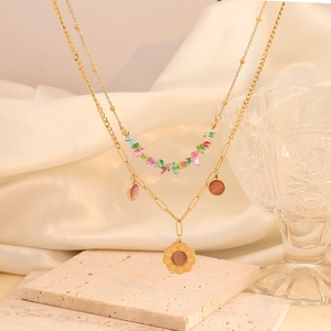 Macro view of gold double-layered necklace with colorful beads and pink flower pendants