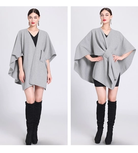 Detail view of a loose grey knitted poncho cape for women styled with a black dress