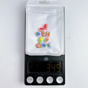 Detailed view of mixed fruit cookie nail charms on a digital scale weighing 3.49g