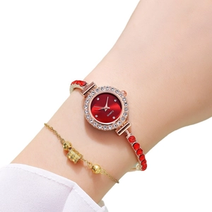 Red rhinestone watch and gold bracelet set on wrist with crystal bezel and quartz dial