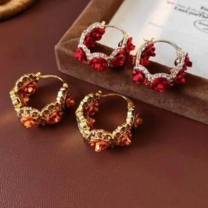 Macro detail of gold-plated hoop earrings with crystal-studded rose flower charms