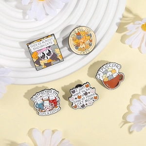 Cute cartoon cat enamel pin set on a decorative white stand with daisy flowers
