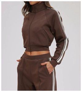 Detail view of brown two-piece tracksuit with white stripes and high-collar zipper