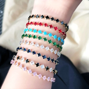 Close-up of stacked 18k gold tennis bracelets featuring vibrant multi-color zircon stones