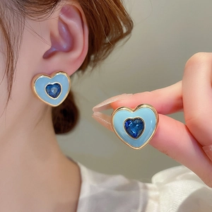 Detail of blue heart-shaped enamel stud earrings with central crystal in gold plating
