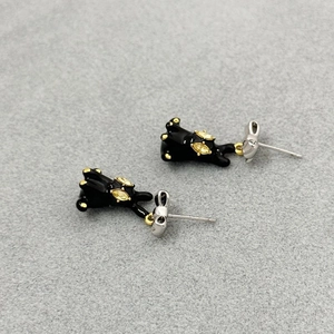 Close-up of black enamel rabbit earrings with bow detail and yellow rhinestone eyes