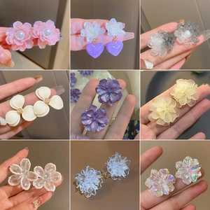 Detailed view of various flower-shaped earrings in multiple colors, textures and styles