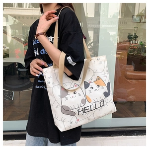 Street style view of canvas tote bag with cartoon cat print and sturdy handles