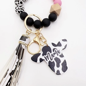 Detail of western cow print keychain with wood beads, fringe tassel and Mama bull pendant