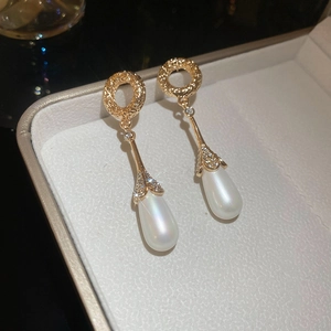 Macro shot of gold-plated French retro earrings with zircon accents and faux pearl drop