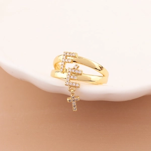 Detail of gold double-layered ring with zircon-paved F-letter and cross charms