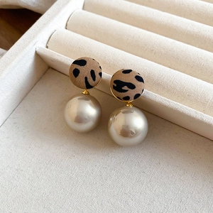 Close-up of leopard print fabric circle earrings with elegant hanging imitation pearls