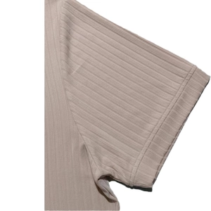 Detailed macro view of the ribbed knit fabric and sleeve stitching on the beige V-neck shirt